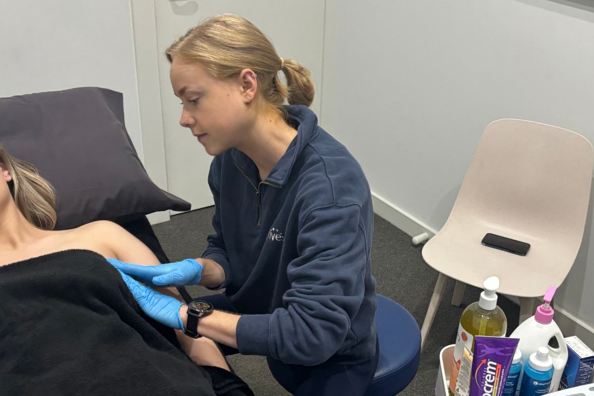 Women's health physiotherapist Sophie provides scar tissue massage and lymphatic drainage massage to a breast cancer survivor who is lying down.